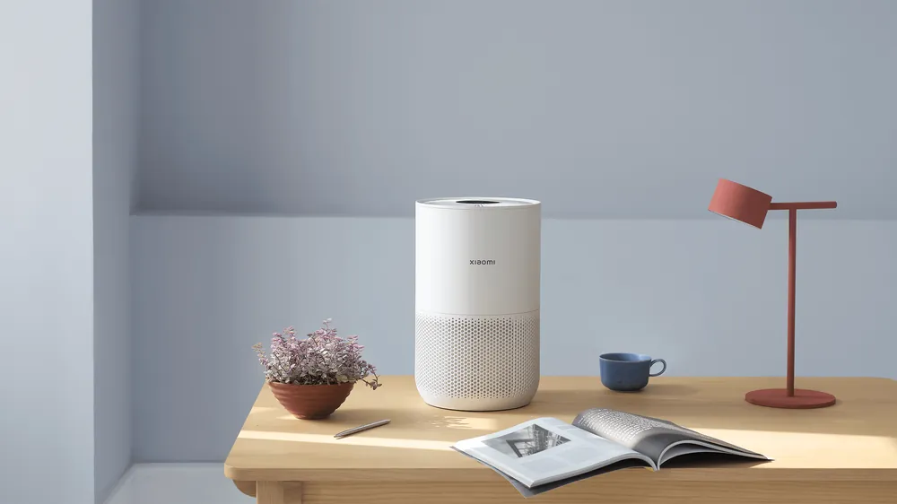 Yozuv stolidagi Xiaomi Smart Air Purifier 4 Compact — Ø22 sm va 2,2 kg silindr