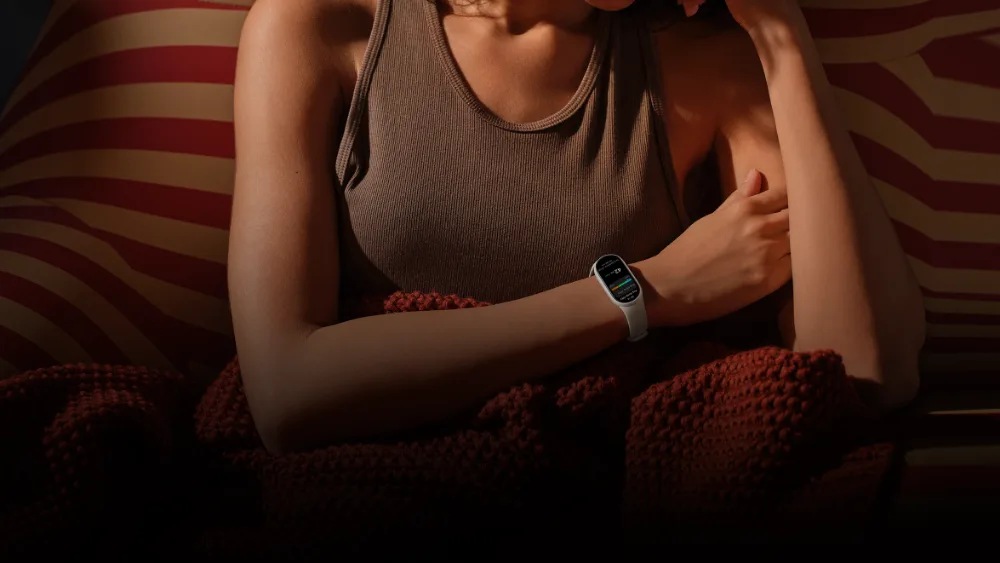 Kechqurun pled ostidagi qiz qoʻlida Smart Band 11 — 15,58 g lik bilaguzuk uyquga xalaqit bermaydi