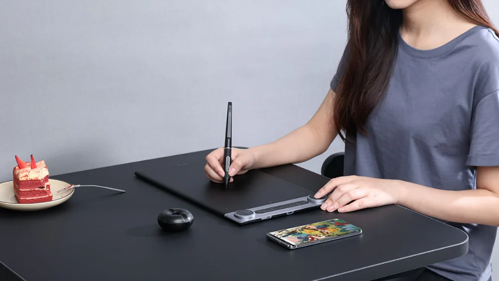 Stol ustida smartfon yonidagi simsiz Huion Inspiroy Dial 2