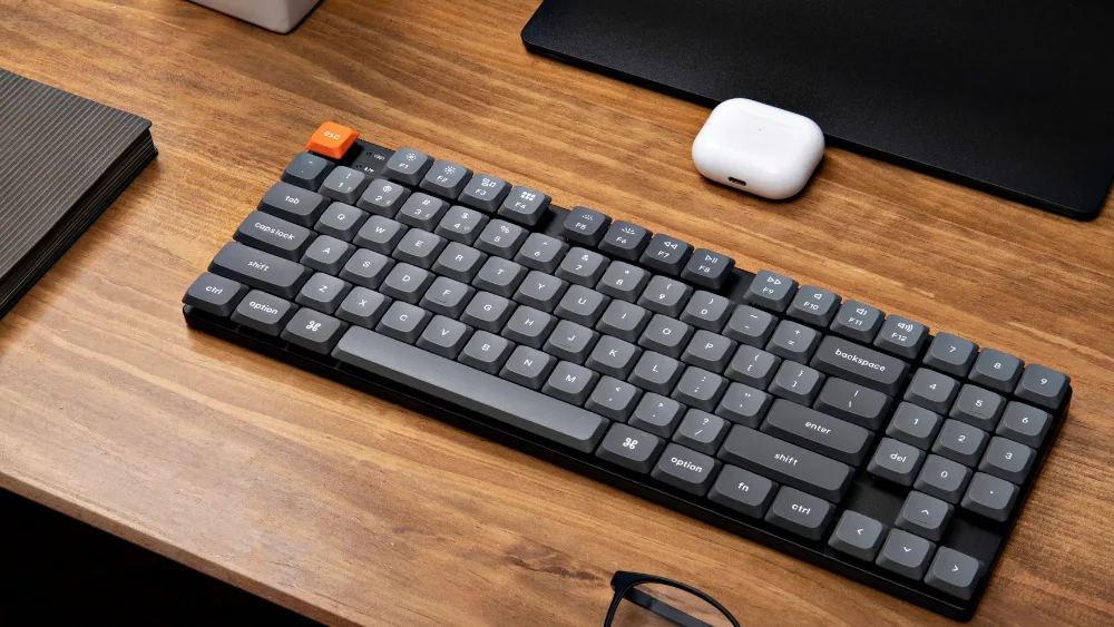 Keychron K13 Max на деревянном столе рядом с подставкой монитора