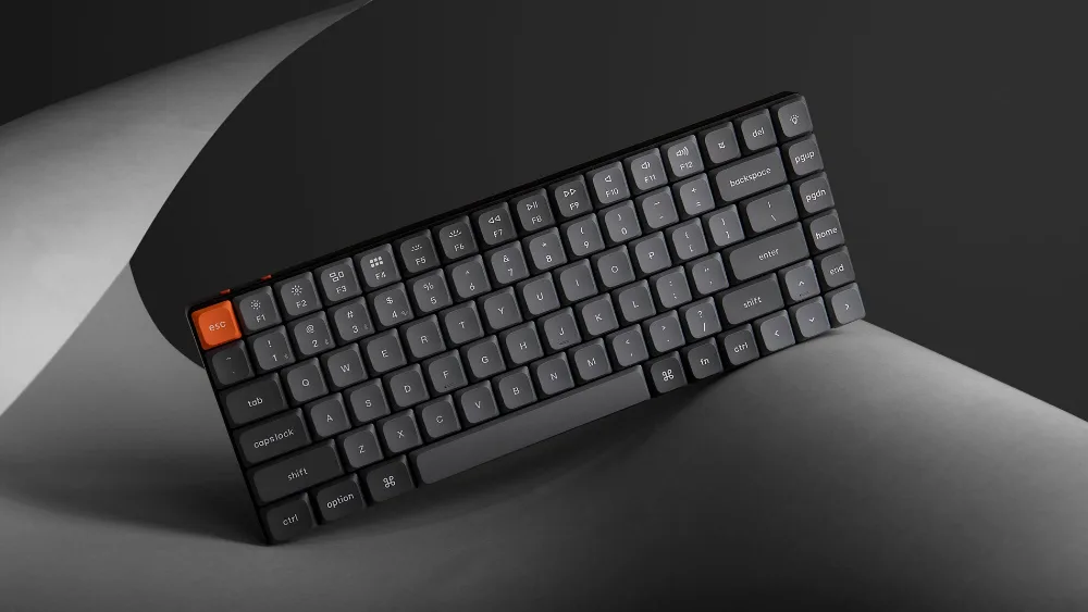 Keychron K3 Max на изогнутом листе бумаги на тёмном фоне