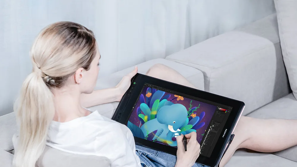 Divandagi qiz Huion Kamvas Pro 16 grafik monitori ekranida toʻgʻridan-toʻgʻri pero bilan chizmoqda