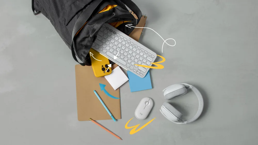 Sichqoncha va quloqchin yonida sumkadan chiqib turgan Logitech Pebble Keys 2 K380s klaviaturasi