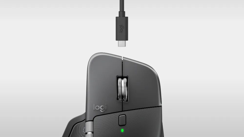 Grafit rangli MX Master 4 yuqoridan, old qirrasi ustida — USB-C kabel shtekeri