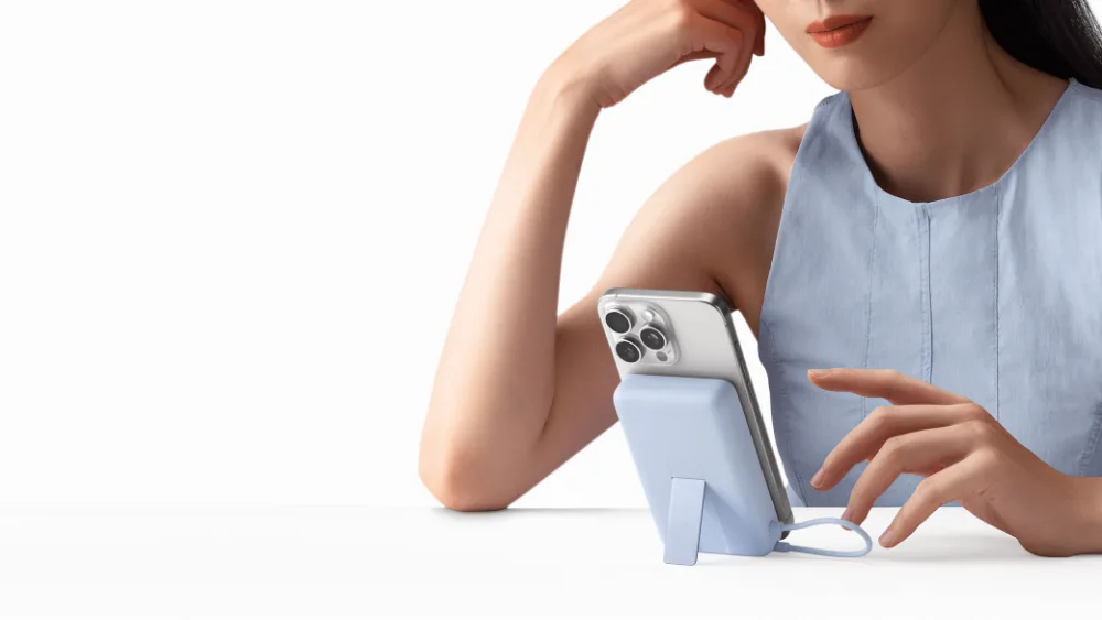 Qiz Xiaomi Magnetic Power Bank 10000 with Built-in Stand tayanchidagi iPhone ga qaramoqda