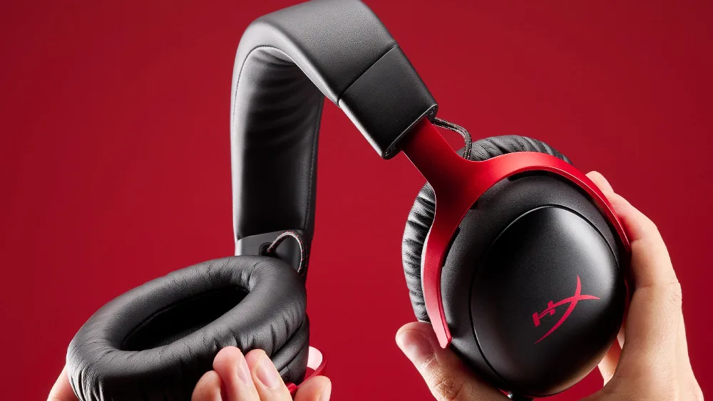 Qoʻllarda HyperX Cloud III S Wireless garniturasining quloq yostiqchalari va bosh tasmasi