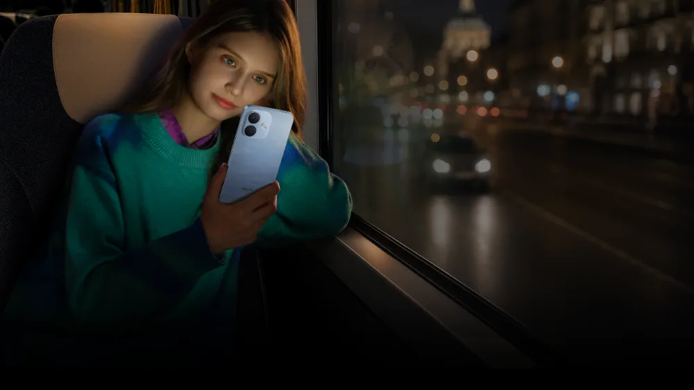 Kechki avtobusda qiz Sky Blue rangidagi Redmi Note 17 Pro 5G ga qaramoqda