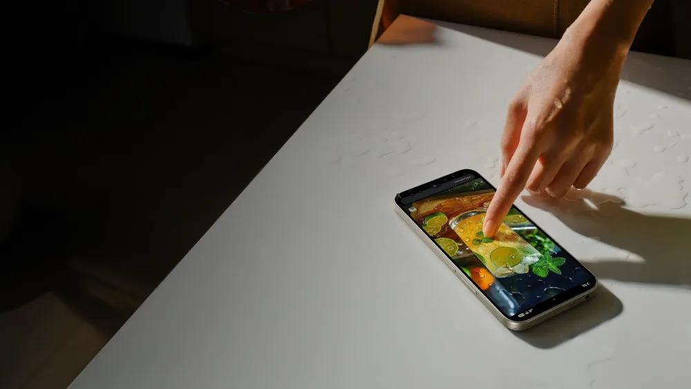 Hoʻl stol ustidagi Redmi 17 ga barmoq tegmoqda — IP64 himoya