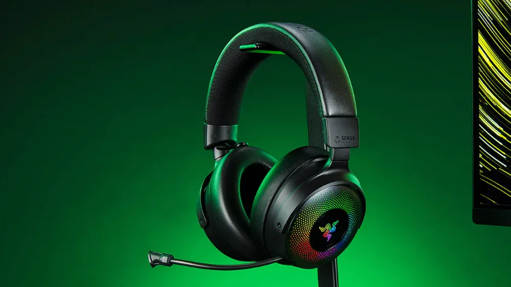 Monitor yonidagi taglikda kosachalari yoritilgan va mikrofonli Razer Kraken V4 Pro