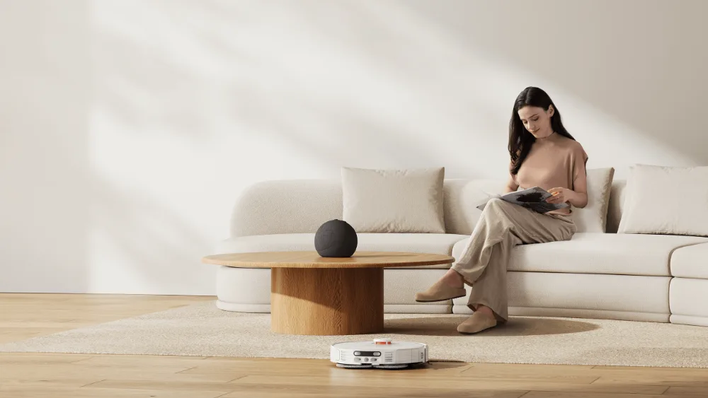 Xiaomi Robot Vacuum H50 Pro убирает гостиную, пока девушка читает на диване