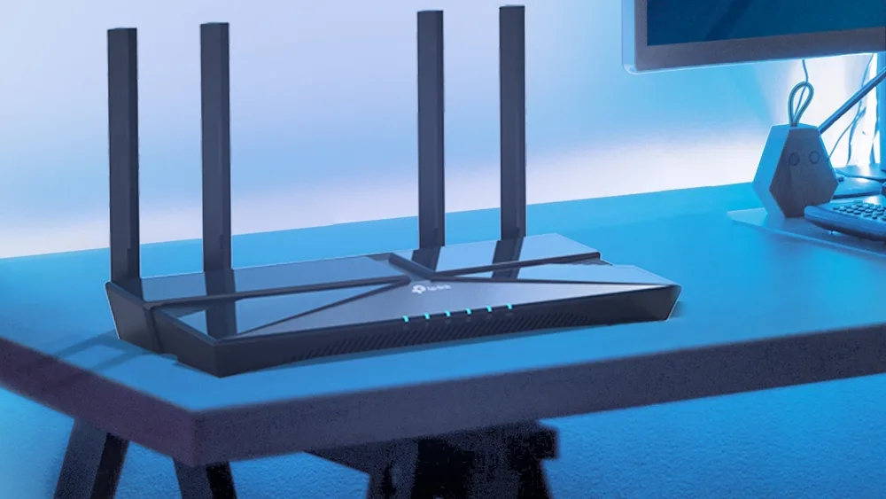 Роутер TP-Link Archer AX53 на столе у монитора с синей подсветкой