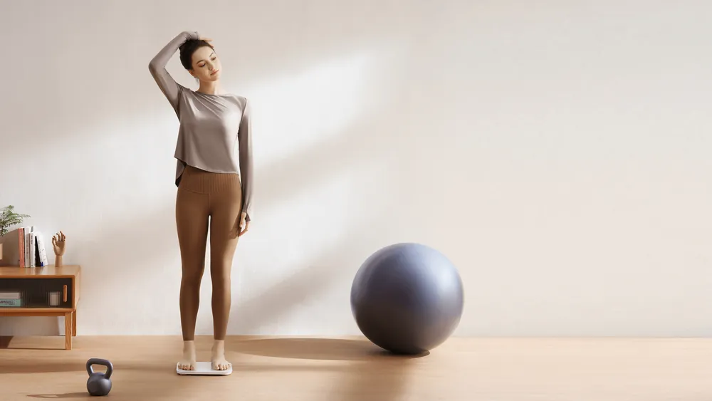 Choʻzilish mashqidan keyin qiz Xiaomi Body Composition Scale S400 tarozisiga chiqmoqda — mashgʻulotlar uchun tana tarkibi